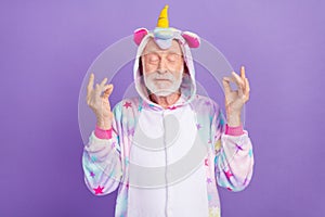 Portrait of attractive dreamy calm grey-haired man wearing kigurumi meditating isolated over violet purple color