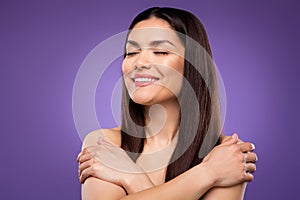 Portrait of attractive dreamy cheerful woman hugging herself enjoying isolated over bright violet purple color