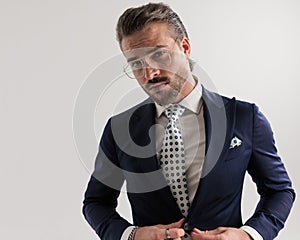 portrait of attractive elegant man with glasses opening navy blue suit