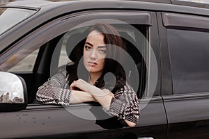 portrait of attractive fabulous brunette woman wearing checkered dress in a lux car. lady in automobile.