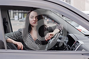 portrait of attractive fabulous brunette woman wearing checkered dress in a lux car. lady in automobile.