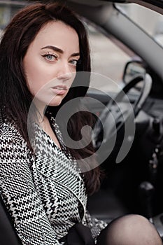 portrait of attractive fabulous brunette woman wearing checkered dress in a lux car. lady in automobile.