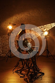 Portrait of attractive female actress. Beautiful woman in golden dress standing near directors chair holding with film