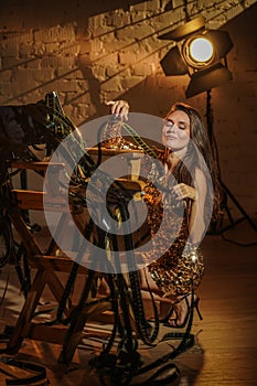 Portrait of attractive female actress. Brunette woman with closed eyes in dress sitting next to directors chair with