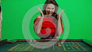 Portrait of attractive female on chroma key green screen close shot. Woman in red dress at roulette table with croupier