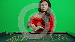 Portrait of attractive female on chroma key green screen close shot. Woman in red dress at the roulette table with smile