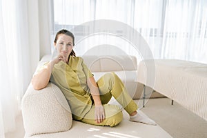 Portrait of attractive female masseuse therapist in uniform sitting posing on couch looking at camera with friendly