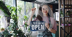 Portrait of attractive florist changing sorry we are closed sign to we are open