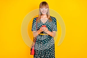 Portrait of attractive focused cheerful girl using gadget browsing media rout gps isolated over bright yellow color