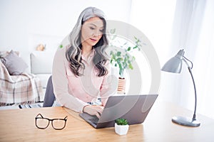 Portrait of attractive focused woman copywriter using laptop writing typing e-mail at home house indoor