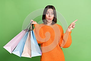 Portrait of attractive funny amazed cheerful girl holding buyings showing copy space new isolated over bright green