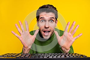 Portrait of attractive funny amazed guy nerd using laptop having fun isolated over vibrant yellow color background