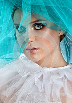 Portrait of attractive girl with beautiful make-up. She has blue-green tulle near her face