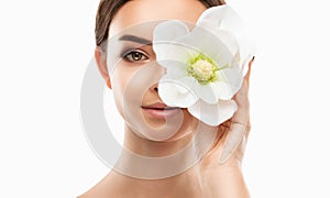 Portrait of attractive girl with healthy clean skin and beautiful make-up. She is holding a white flower near her face.