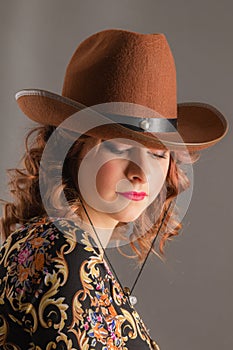 Portrait of an attractive girl with lowered eyes in a cowboy hat