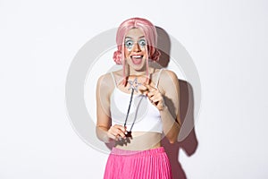 Portrait of attractive girl with pink wig and bright makeup, dressed up as a fairy for halloween party, holding magic