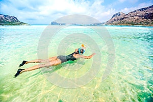 Portrait of attractive girl wearing black swimsuit and snorkling in clear ocean water photo