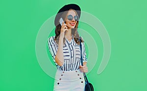 Portrait attractive happy smiling young woman calling on a smartphone wearing a black round summer hat, white striped shirt on