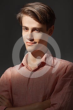 Portrait of attractive kind young man with folded and crossing hands standing Isolated on black background and looking