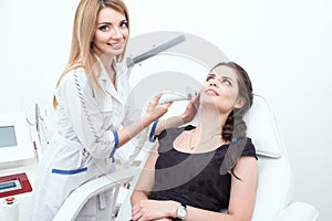 A portrait of an attractive lady cosmetologist providing laser facial treatment.