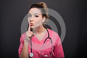 Portrait of attractive lady doctor showing silence gesture photo