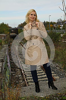 Portrait of an attractive lady in sunglasses posing in front of train tracks