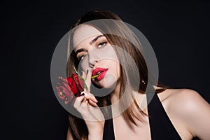 Portrait of attractive lovely charming dreamy girl holding red roses, isolated on black studio background.