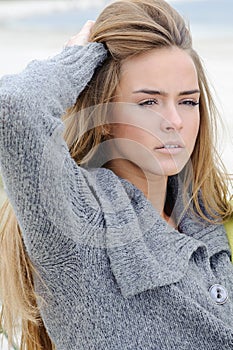 Portrait of the attractive lovely woman sits in the sand dune of a beach relaxing - autumn, beach, sea. Woman in the sand dunes