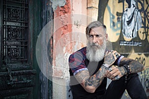 Portrait of an attractive man with a beard and tattoos in front of a green door