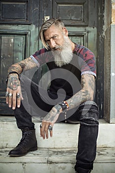 Portrait of an attractive man with a beard and tattoos in front of a green door