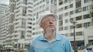 Portrait of attractive man in hat on background of city buildings, camera tracking