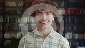 Portrait of Attractive Man Student Standing in Front of the Camera and Laughing in High School Library. Education