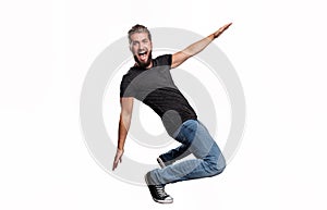Portrait of an attractive man who is pretending to drive on a skateboard in front of a white background