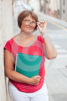 Portrait of attractive mature woman with a business folder and glasses.