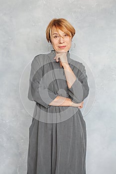 Portrait of attractive mature woman 60 years old. Pretty senior lady in gray dress