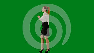 Portrait of attractive office girl on chroma key green screen. Woman in skirt and blouse walking cutely. Side view.