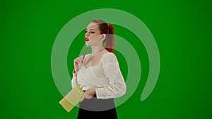 Portrait of attractive office girl on chroma key green screen. Woman in skirt and blouse walking holding notebook and