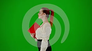 Portrait of attractive office girl on chroma key green screen. Woman in skirt and blouse walking with paper folder and