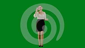 Portrait of attractive office girl on chroma key green screen. Woman in skirt walking talking on smartphone by video