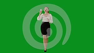 Portrait of attractive office girl on chroma key green screen. Woman in skirt walking talking on smartphone by video