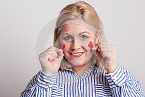 Portrait of an attractive overweight woman holding hearts on her cheeks.