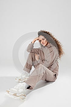 Portrait of an attractive pensive young woman in casual sportswear sitting over white background, isolated with copy