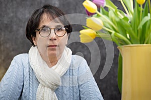 Portrait of attractive senior brunette woman with glasses sitting