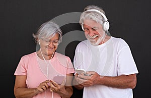Portrait of attractive senior couple using mobile phones. Elderly retiree enjoying social and tech.  Black background