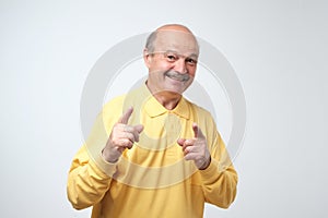 Portrait of attractive senior man pointing with forefingers at you, smiles broadly with teeth