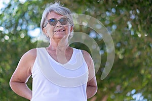 Portrait of attractive senior woman white dressed in outdoor under a tree