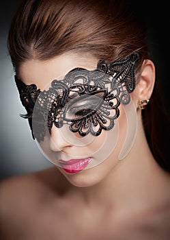 Portrait of attractive sensual young woman with mask. Young attractive brunette lady posing on grey background in studio. Portrait