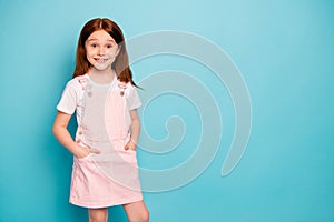 Portrait of attractive small child she her hands plams pocket standing isolated over blue background