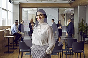 Portrait of attractive smiling brunette business coach trainer woman in office looking at camera.