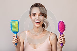 Portrait of attractive smiling woman holding hairbrushes